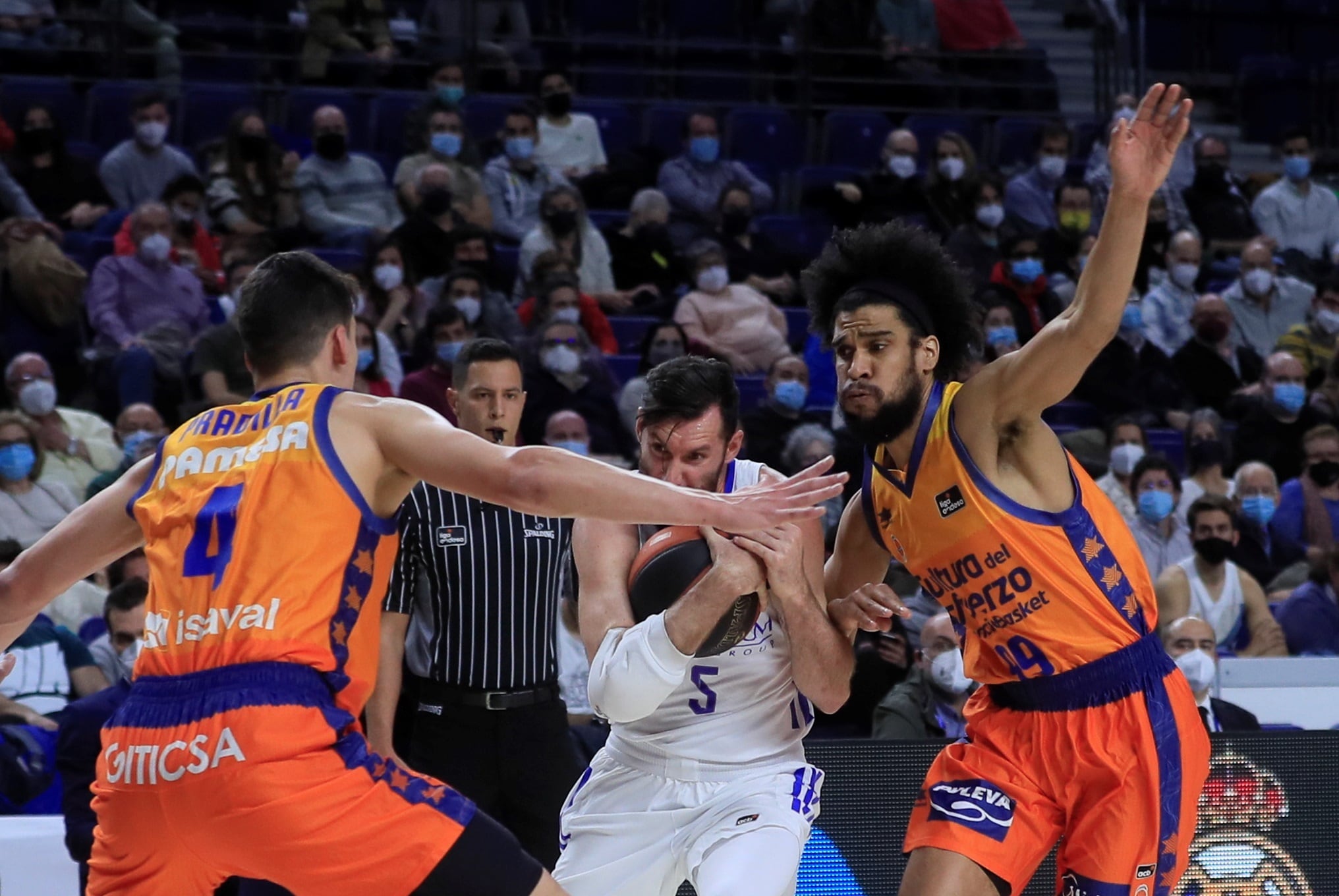 El alero del Real Madrid Rudy Fernández (c) trata de jugar un balón entre Louis Labeyrie (d) y Jaime Pradilla, ambos del Valencia Basket, durante el partido de la Liga ACB de baloncesto que disputan este domingo en el WiZink Center, en Madrid.