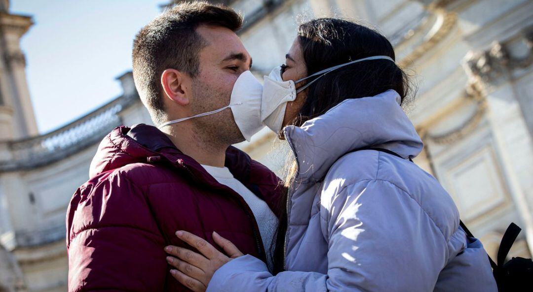 Imagen de archivo de una pareja dándose un beso, entre mascarillas 