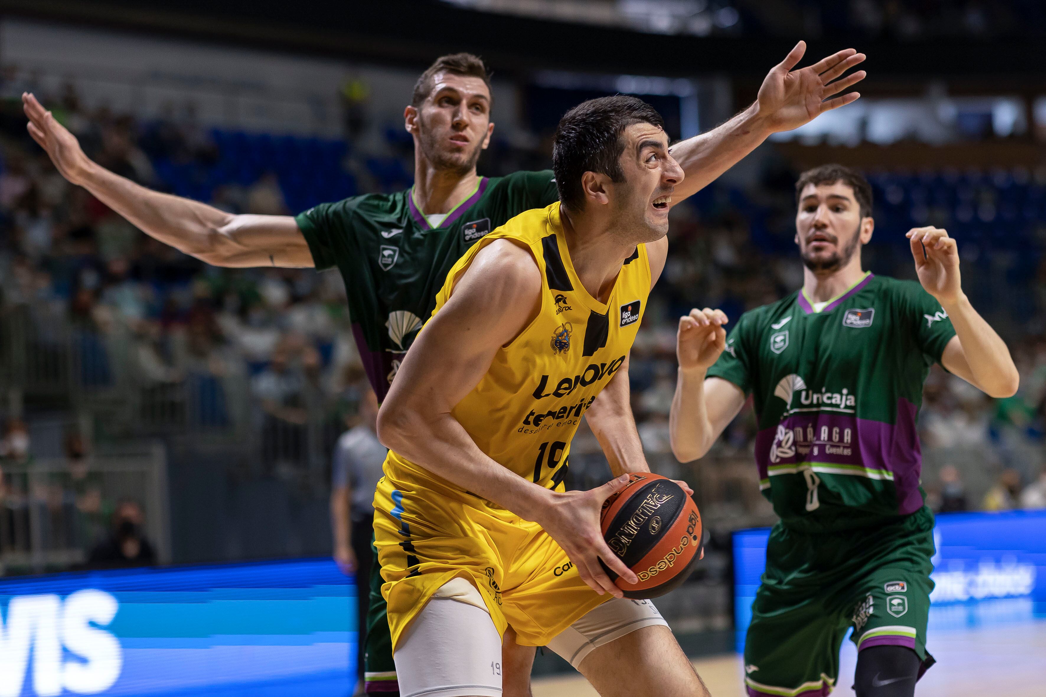 GRAF2331. MÁLAGA, 17/04/2022.- El pivot georgiano del Lenovo Tenerife Gio Shermadini (c) es defendido por el pivot del Unicaja Rubén Guerrero (i) durante la vigésimo novena jornada de la Liga Endesa disputado esta mañana en el Palacio de los Deportes José María Martín Carpena. EFE/Carlos Díaz