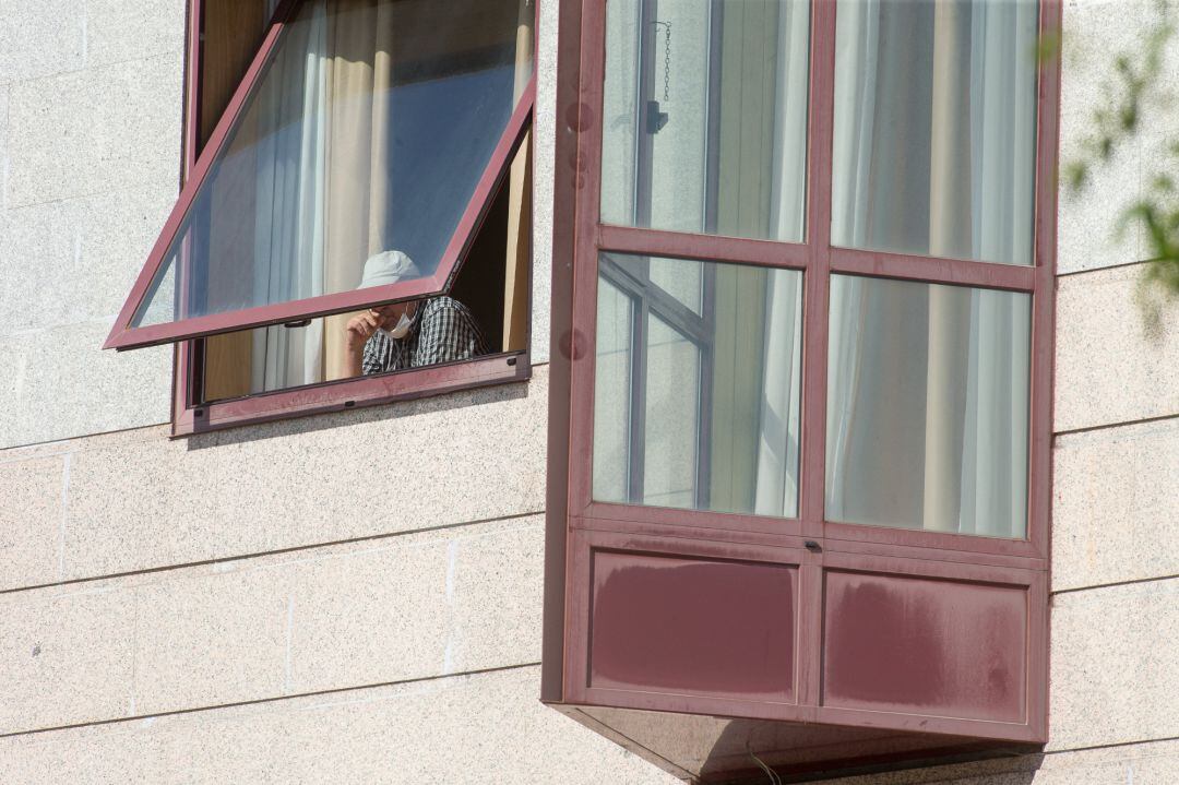 Una persona se asoma por la ventana de la residencia de mayores