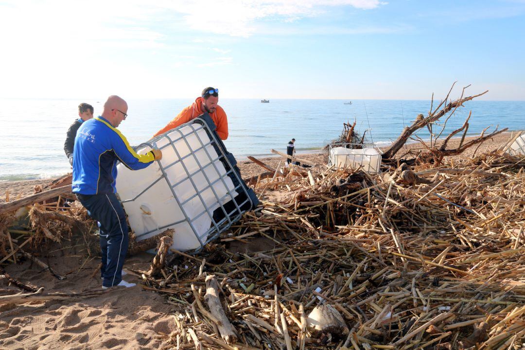 Imatge d'uns voluntaris retirant un gran contenidor de plàstic de la platja de Malgrat de Mar