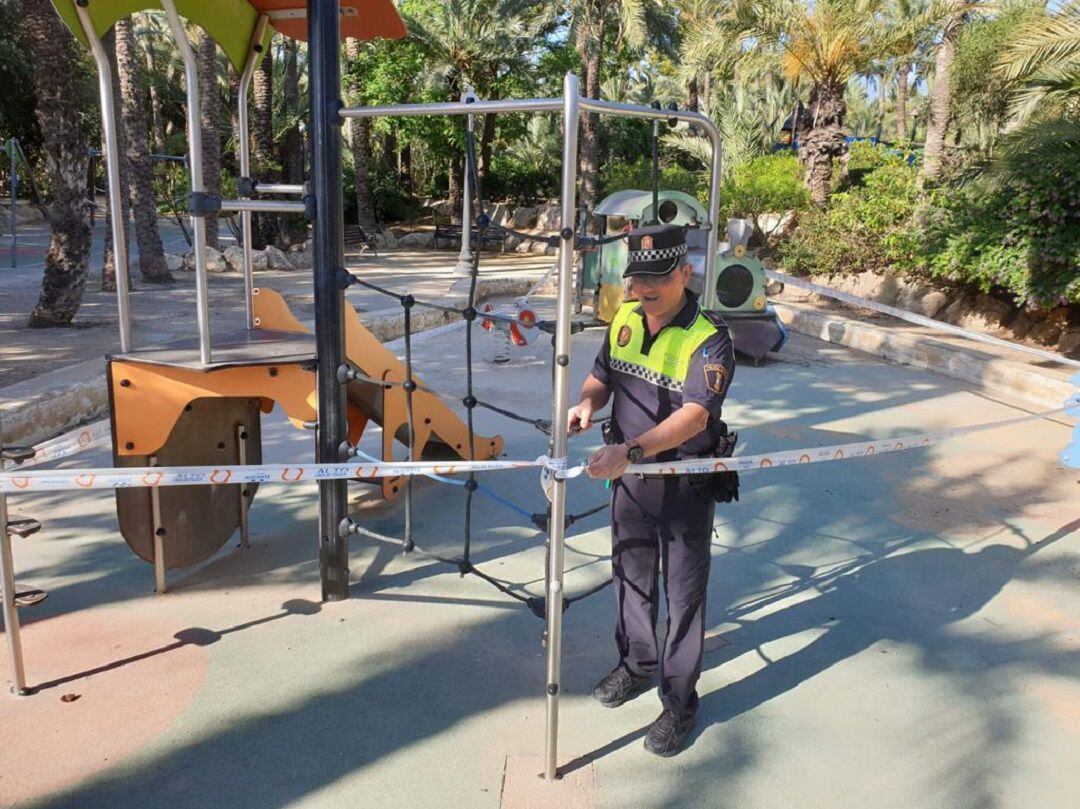 Un agente de la Policía Local retirando el precinto de uno de los parques infantiles de la ciudad