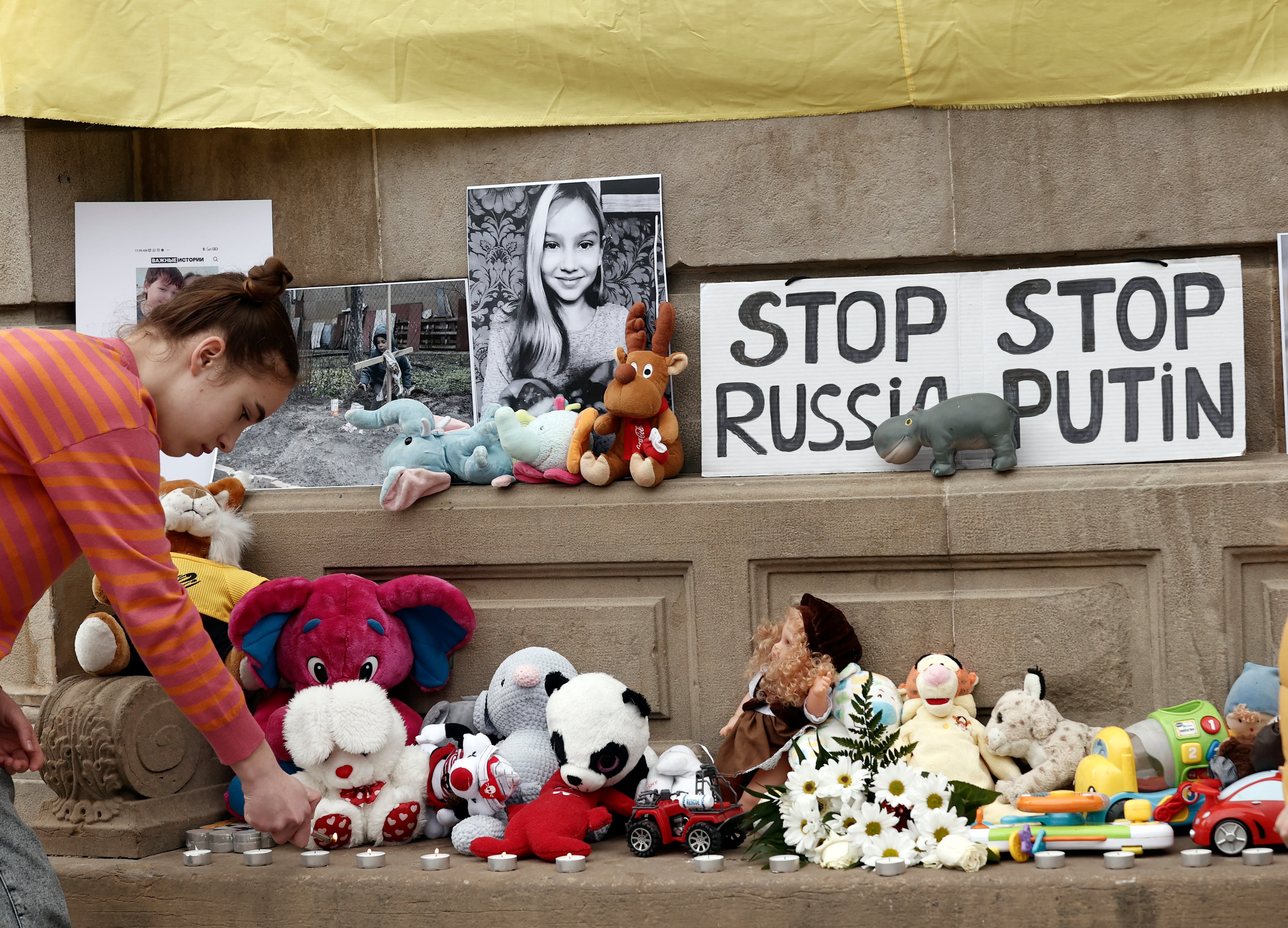 La Asociación de Ucranianos de Navarra Berehynia durante una concentración silenciosa en la que han depositado en el suelo fotos con imágenes de la guerra, velas por los compatriotas fallecidos y juguetes en recuerdo por los niños muertos durante la invasión de Rusia.