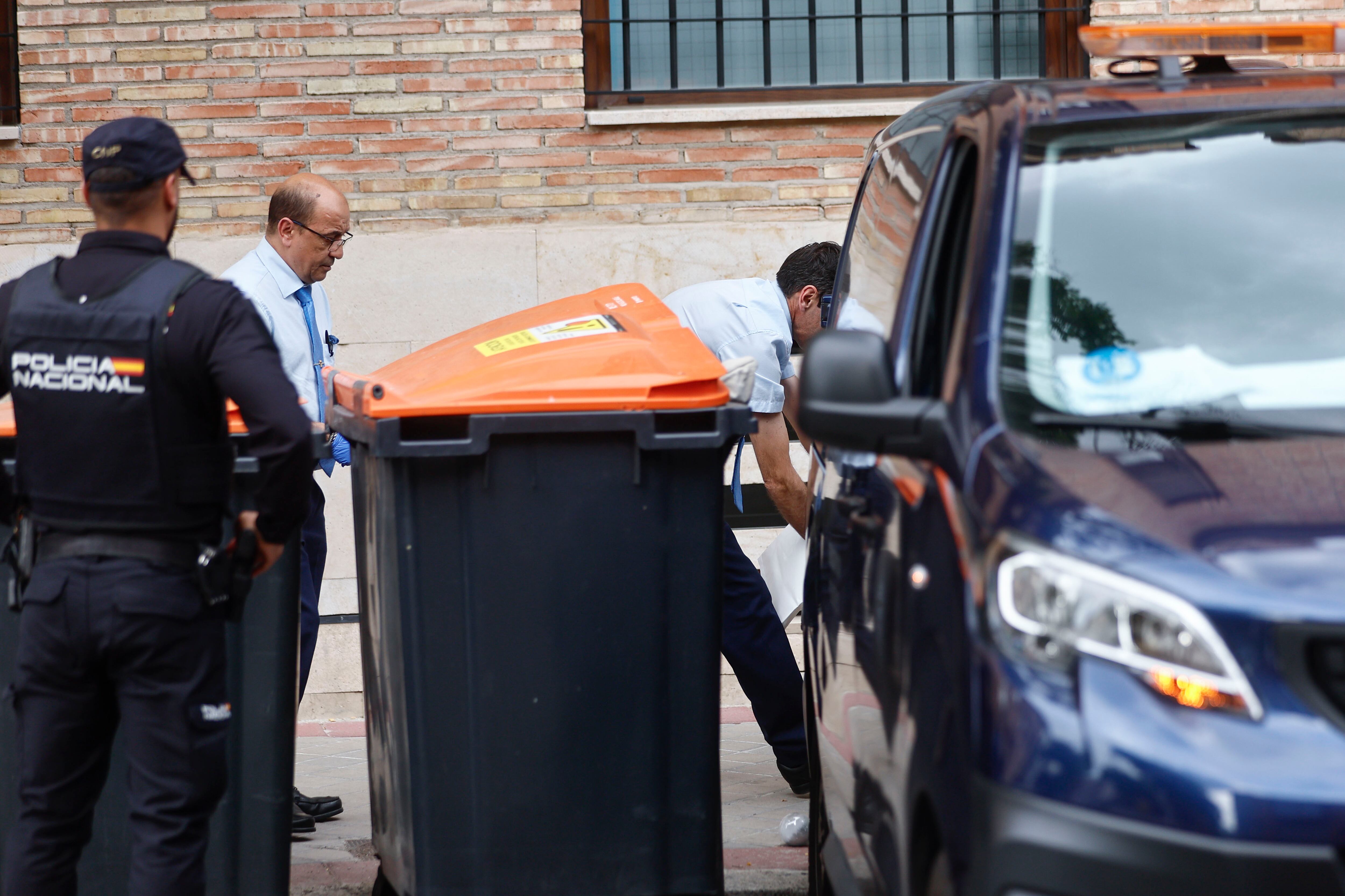 Miembros de los servicios funerarios trabajan en el lugar en que la Policía Nacional investiga el hallazgo del cadáver de un bebé de unos tres meses entre unos cubos de basura del distrito madrileño de Barajas.