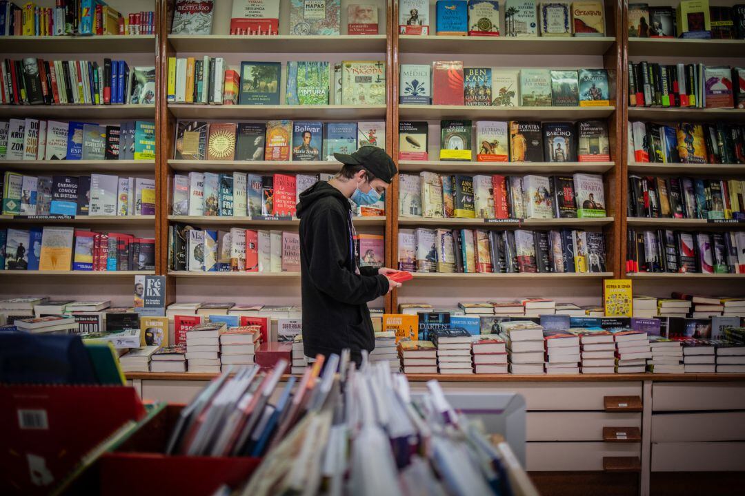 Un joven observa un libro en una librería