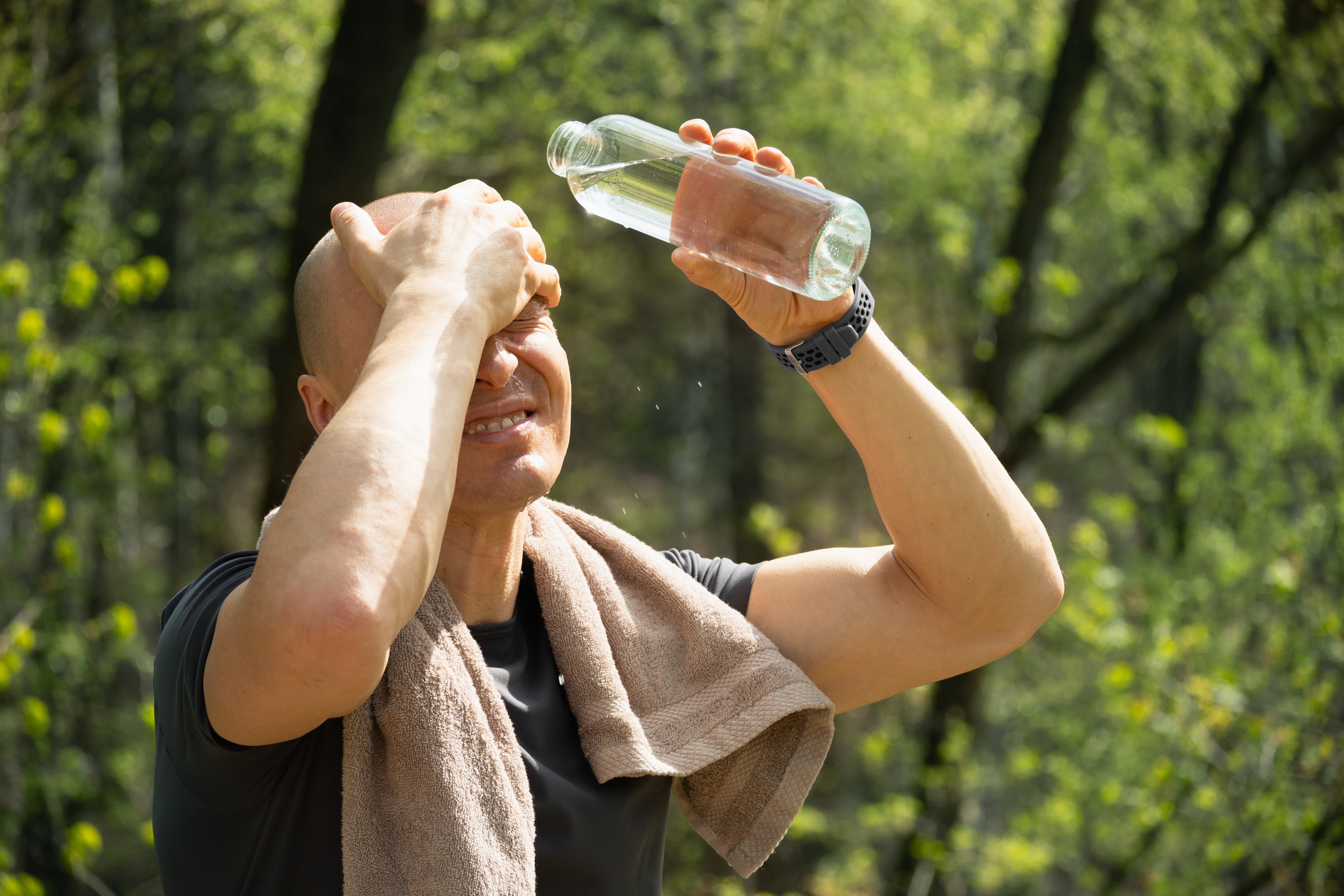 Hombre deportista se refresca con agua durante un día caluroso de verano.