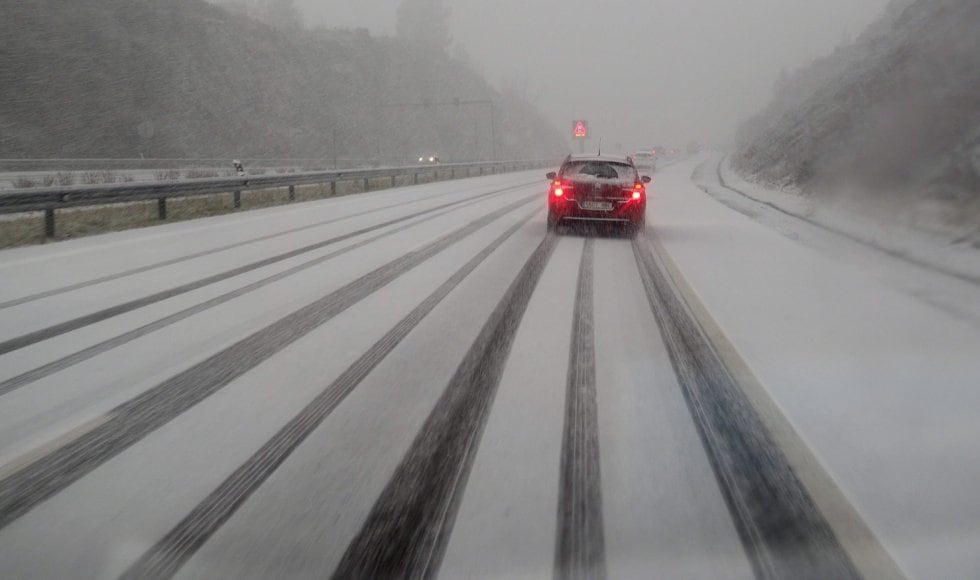Un coche circula por la autovía A-6, en dirección A Coruña, que se encuentra cubierta por la nieve caída en las últimas horas .