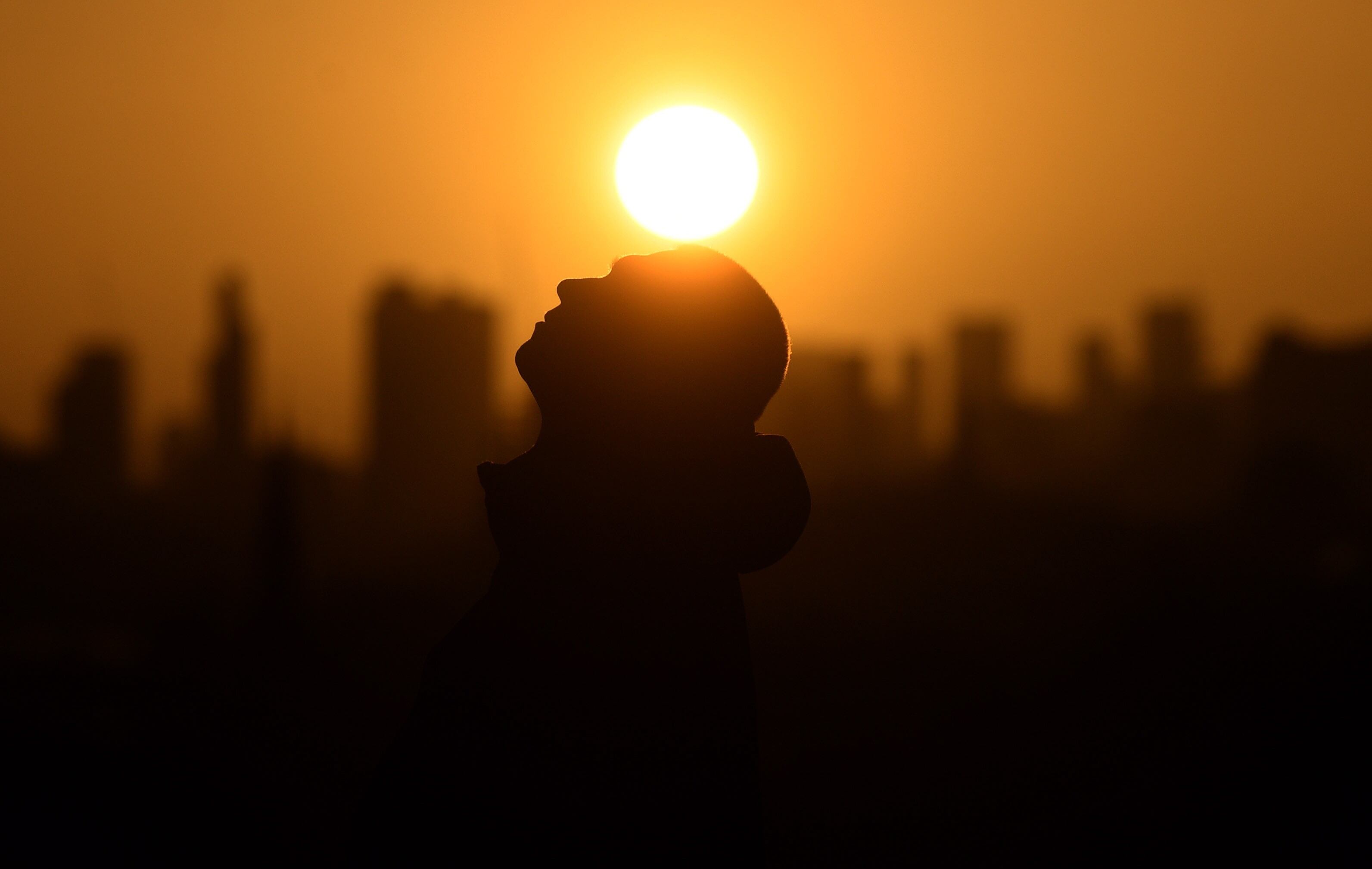 London (United Kingdom), 17/02/2022.- A man relaxes as the sun rises behind the London skyline, at Primrose Hill, Britain, 17 February 2022. (Reino Unido, Londres) EFE/EPA/NEIL HALL
