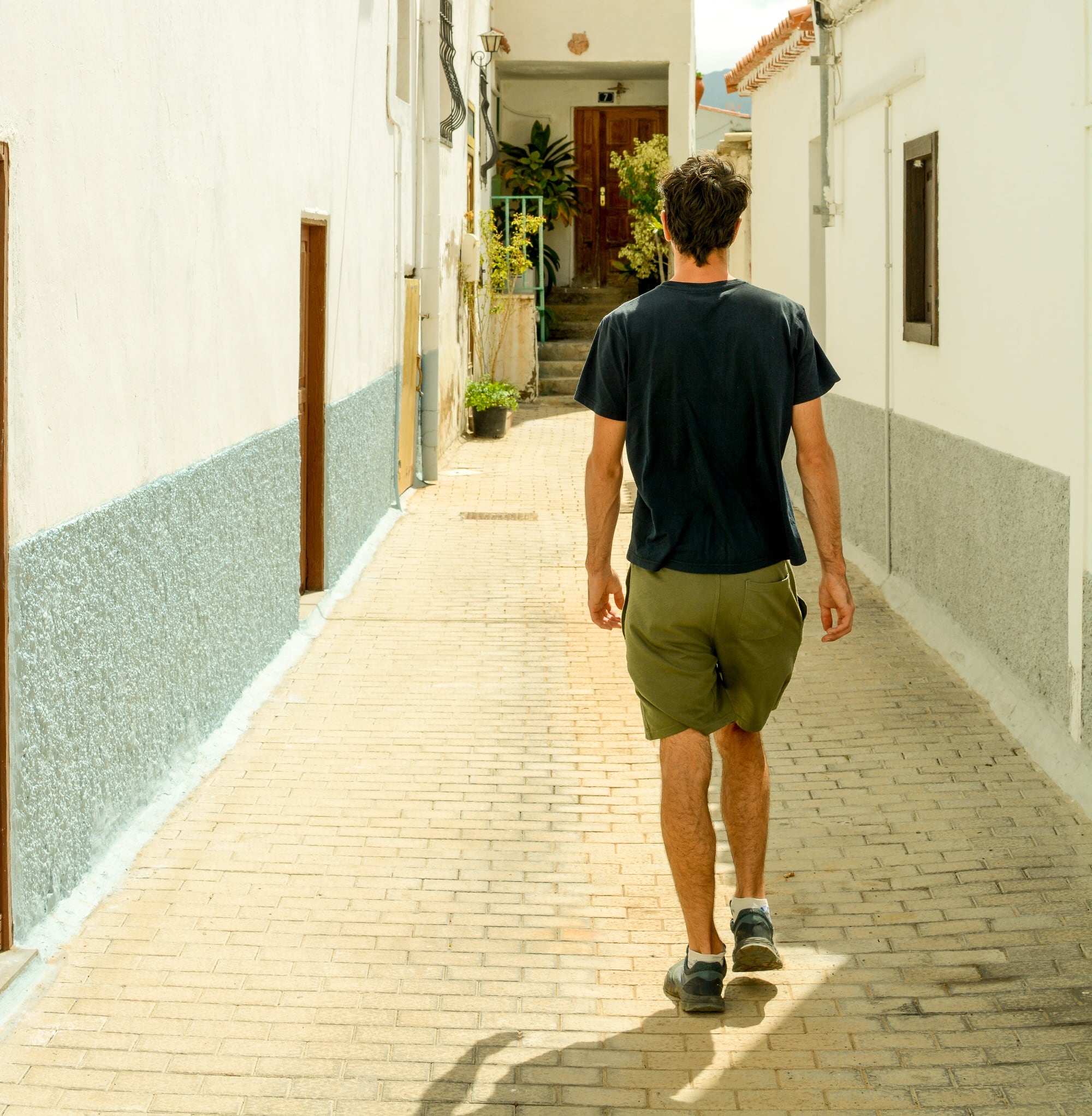 Un hombre pasea por una calle estrecha durante un día de verano