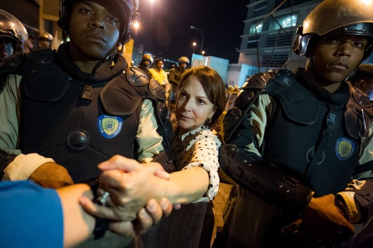 La esposa del alcalde mayor de Caracas Antonio Ledezma, Mitzy Capriles (c), saluda a seguidores en medio de miembros de la Policía Nacional Bolivariana (PNB) que custodian el edificio del Servicio Bolivariano de Inteligencia Nacional (SEBIN).