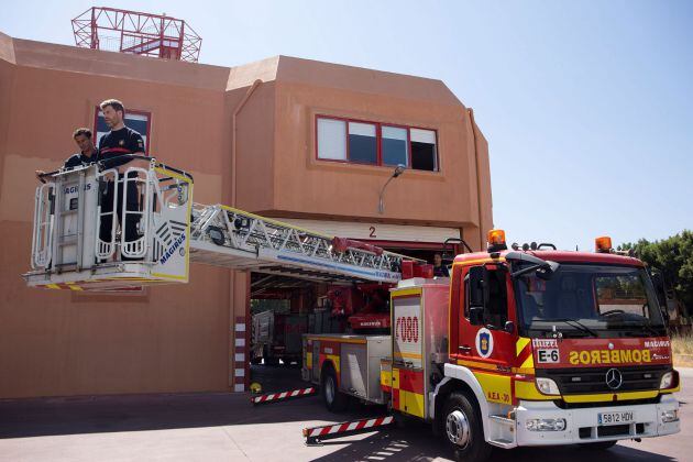 Luis Palma (i) y Daniel Arreza (d), los bomberos que ayer rescataron a una niña de 5 años que se encontraba colgada del balcón de un octavo piso de Málaga, manipulan la autoescala de treinta metros con la que accedieron a la fachada del edificio