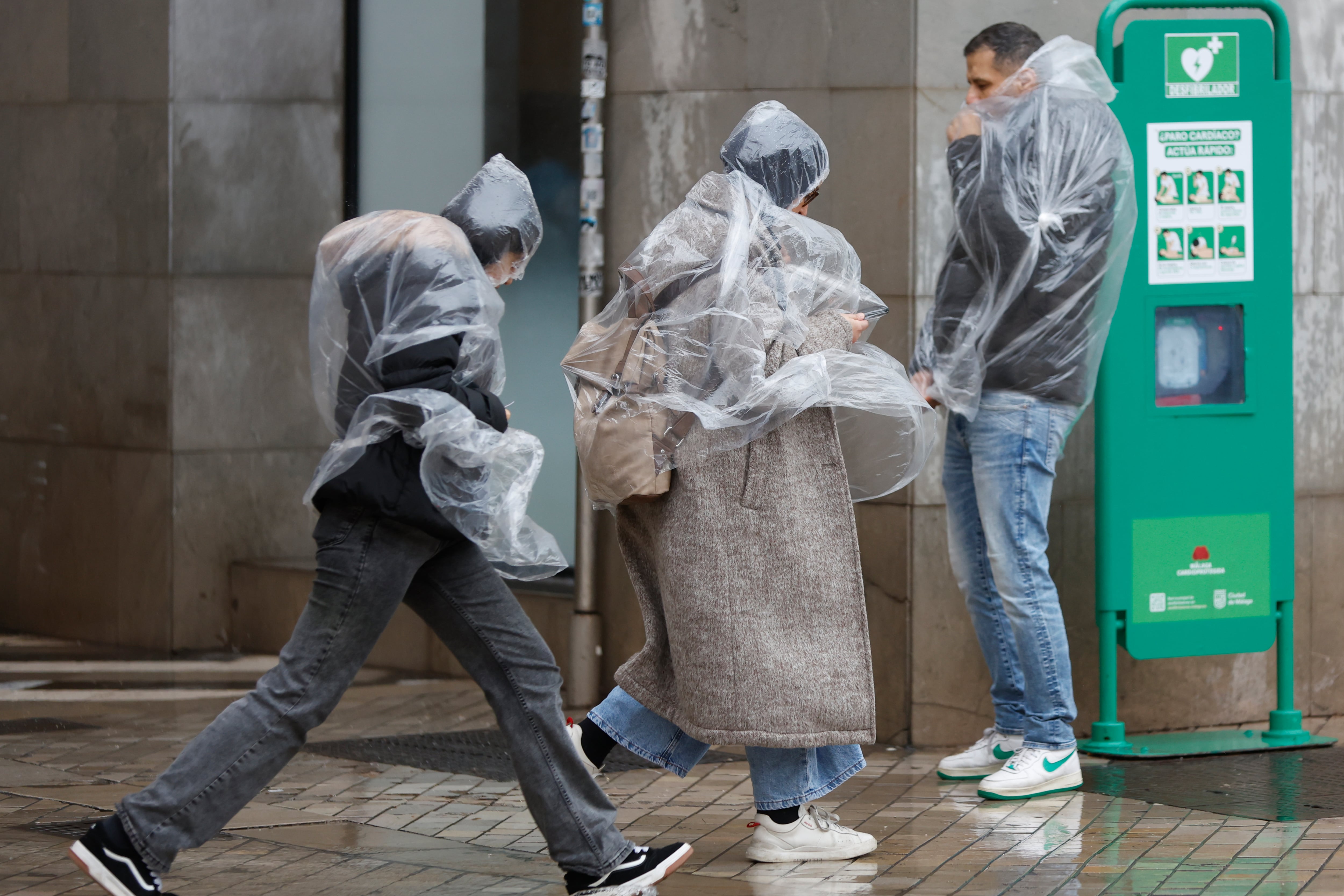 MÁLAGA, 28/01/2026.- Varias personasse protegen de la lluvia y el viento que se registra este miércoles en Málaga. La borrasca Kristin complica este miércoles la jornada meteorológica en Andalucía, donde las clases están suspendidas en 77 municipios de la comunidad, con aviso rojo por viento en Valle del Almanzora y Los Vélez en Almería, y naranjas y amarillos por viento, lluvia y fenómenos costeros en el resto. EFE/ Jorge Zapata