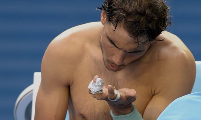 El tenista español Rafa Nadal se observa la mano durante un descanso del partido ante el japonés Kei Nishikori en el Abierto de Australia.