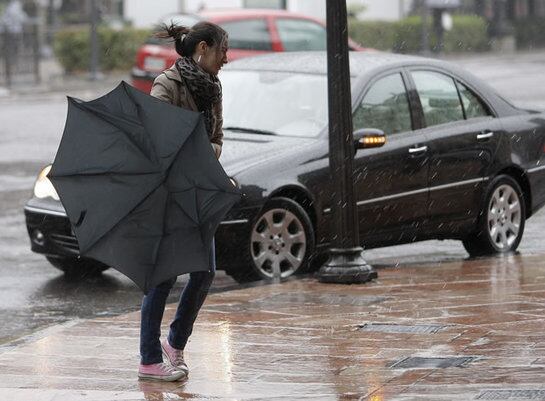 Una mujer tiene dificultades con su paraguas en una jornada de lluvia y viento debido al temporal que azota el norte de la Península.