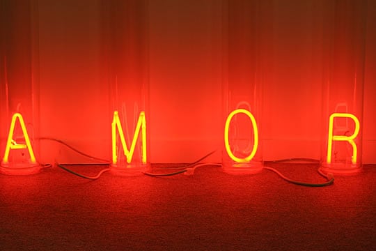 Instalación de la palabra AMOR hecha con luces de neón dentro de tubos transparentes.