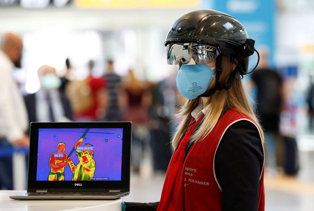 Una oficial del aeropuerto de Fiumicino (Roma) lleva un casco que mide a distancia la temperatura a los pasajeros