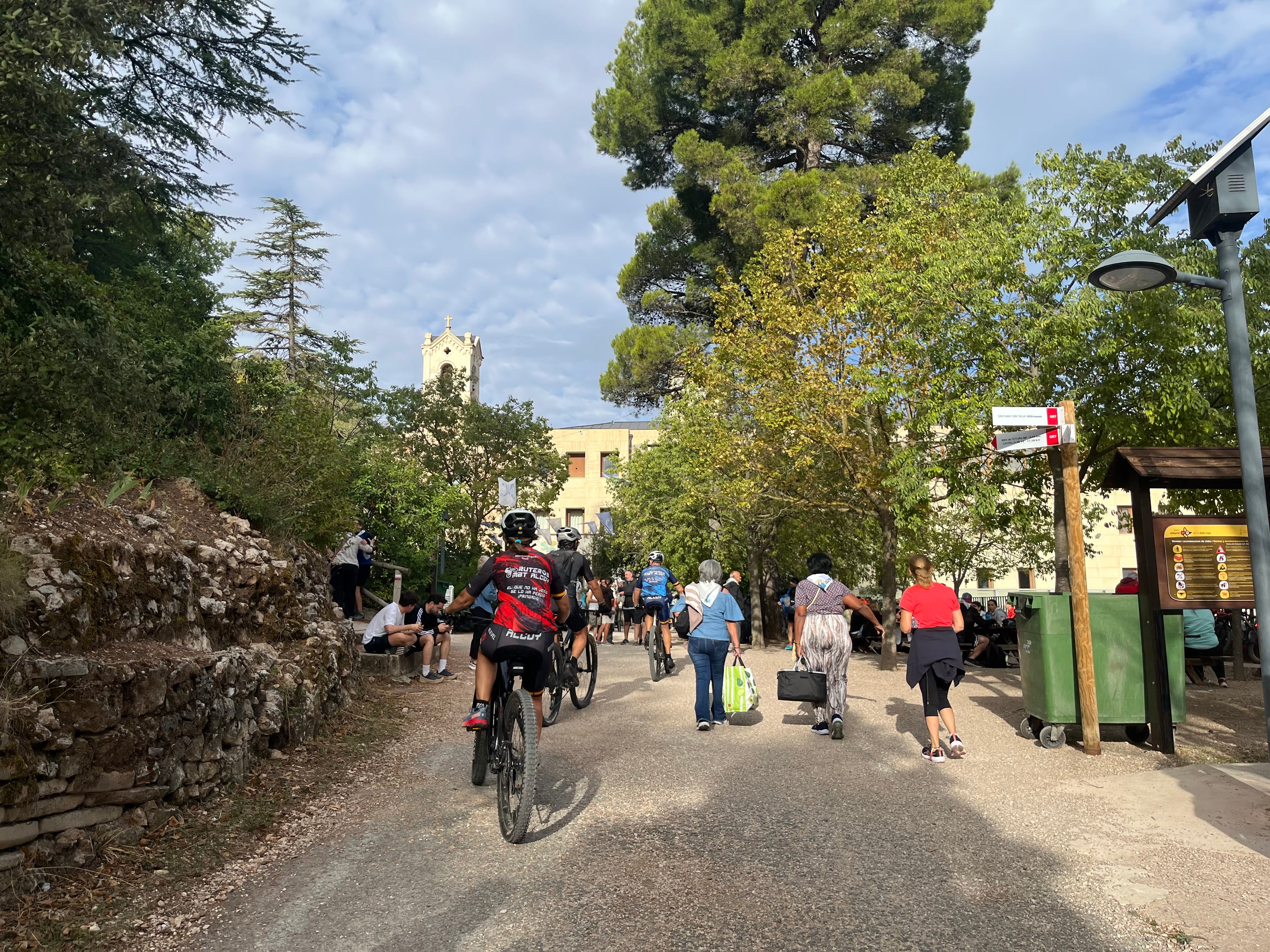 Asistentes, a pie o en bicicleta, dirigiéndose a la explanada de la Font Roja.