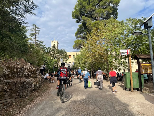 Asistentes, a pie o en bicicleta, dirigiéndose a la explanada de la Font Roja.