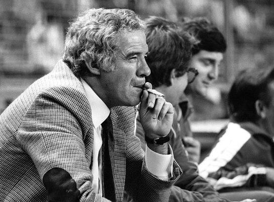 Luis Aragonés, entrenador del Atlético de Madrid en octubre de 1983, fuma en el banquillo en el transcurso de un partido de fútbol.