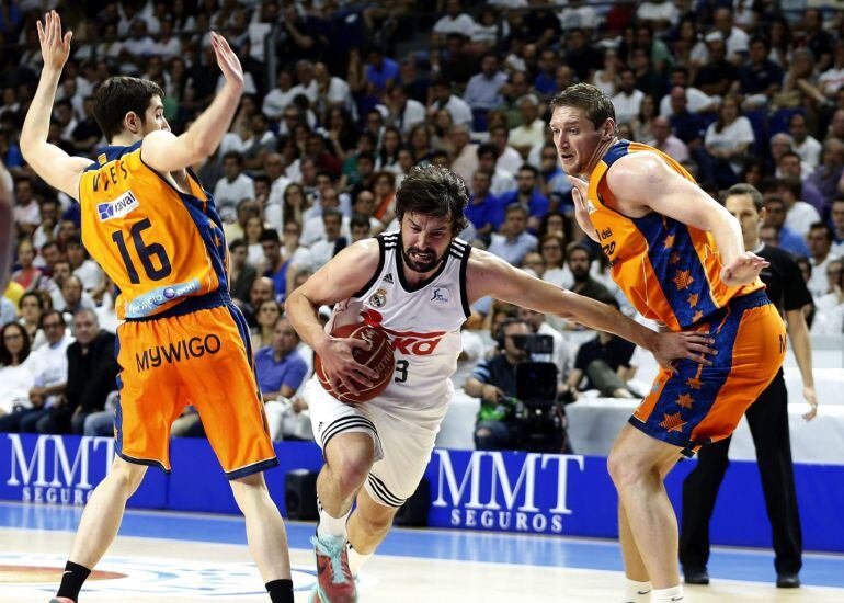 El base del Real Madrid Sergio Llull pugna un balon con el ucraniano Serguéi Lischuk y Guillem Vives, del Valencia Basket