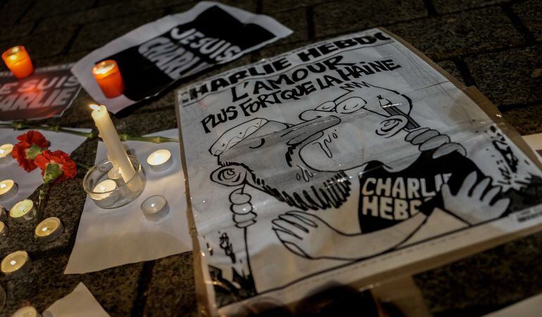 BERLIN, GERMANY - JANUARY 08:  A cartoon lies on the ground while people gather at a vigil in front of the French Embassy following the terrorist attack in Paris on January 7, 2015 in Berlin, Germany. Twelve people were killed including two police officer