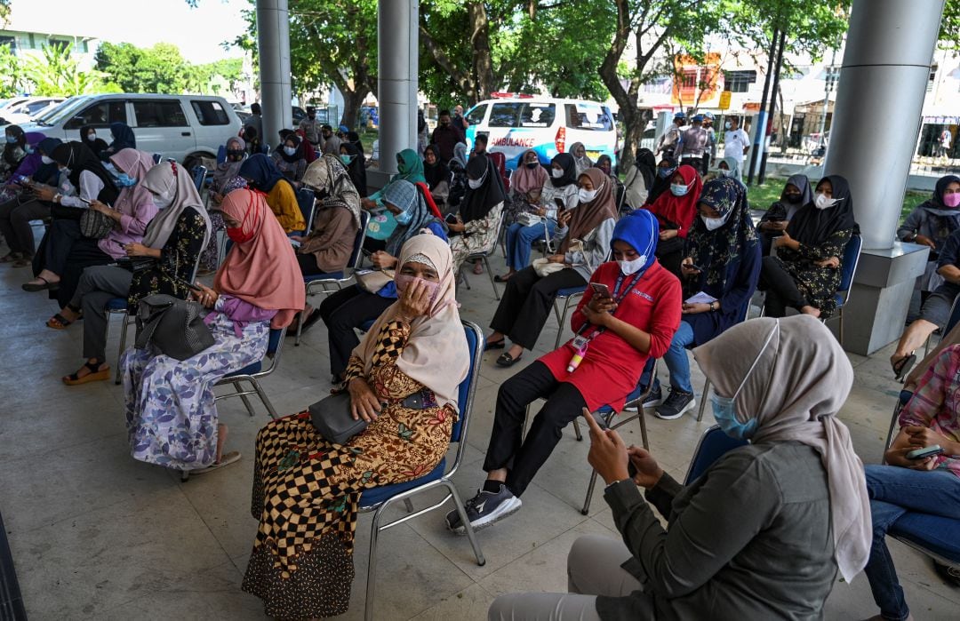 Varias personas esperan en un punto de vacunación en Indonesia.