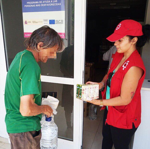 Una voluntaria de Cruz Roja ofrece zumos y agua a una persona ante la ola de calor