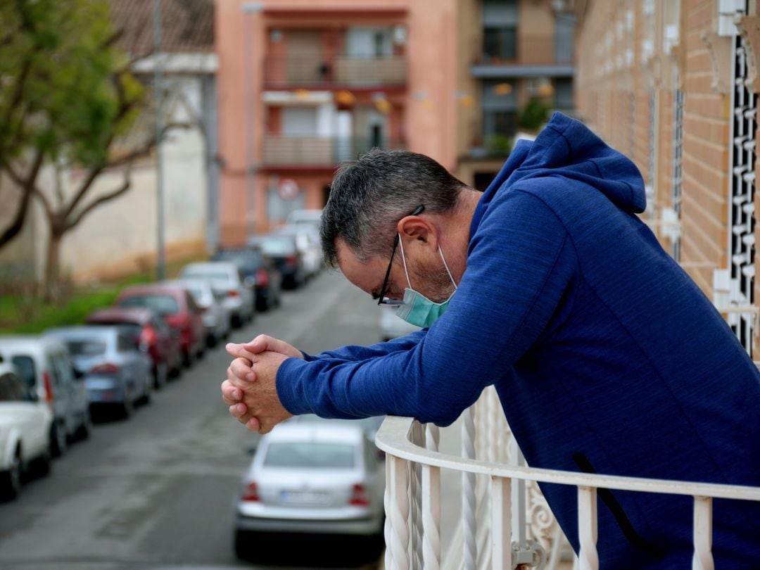 Un hombre con mascarilla en la terraza de una vivienda