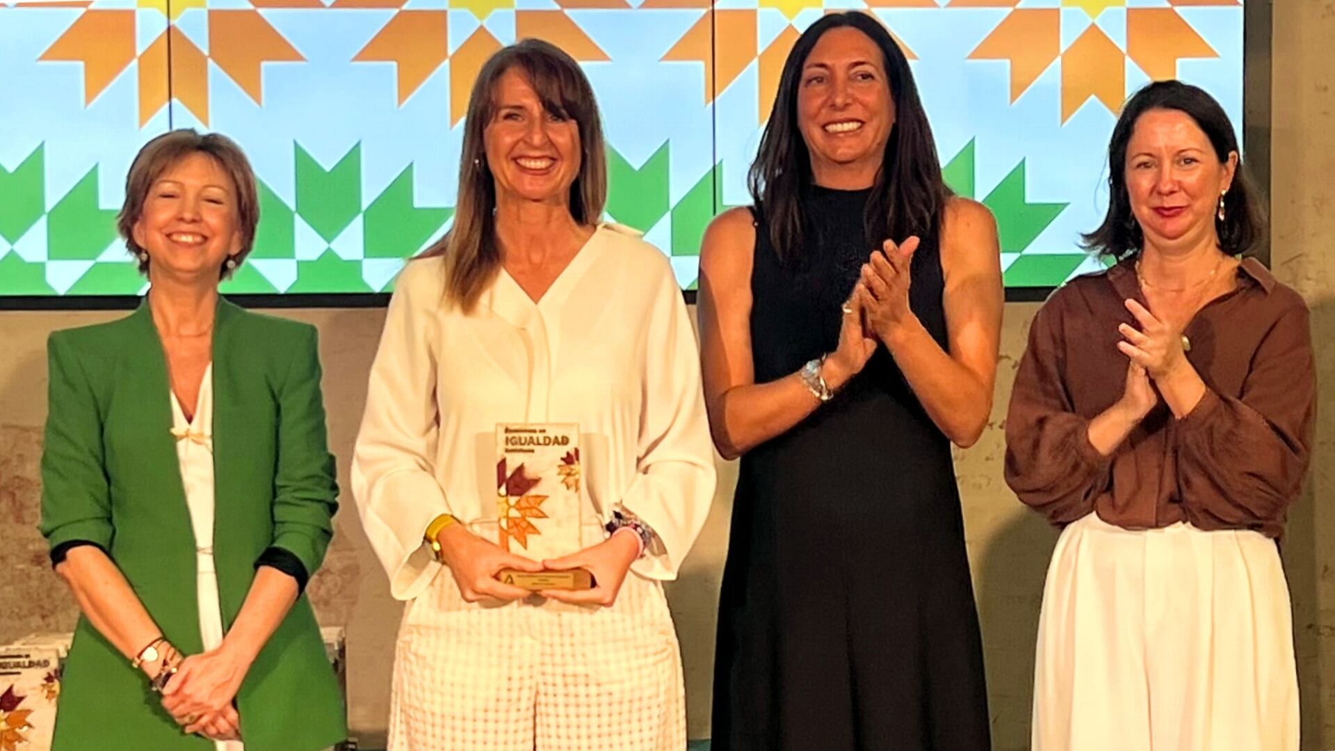 La consejera de Inclusión Social, Juventud, Familias e Igualdad, Loles López, y la directora del Instituto Andaluz de la Mujer, Olga Carrión. hacen entrega de la distinción a la directora general de Audiolís, Juana Cózar