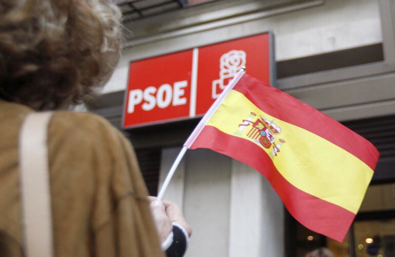 Una persona ondea una bandera española en la sede central del PSOE en la calle Ferraz de Madrid. 