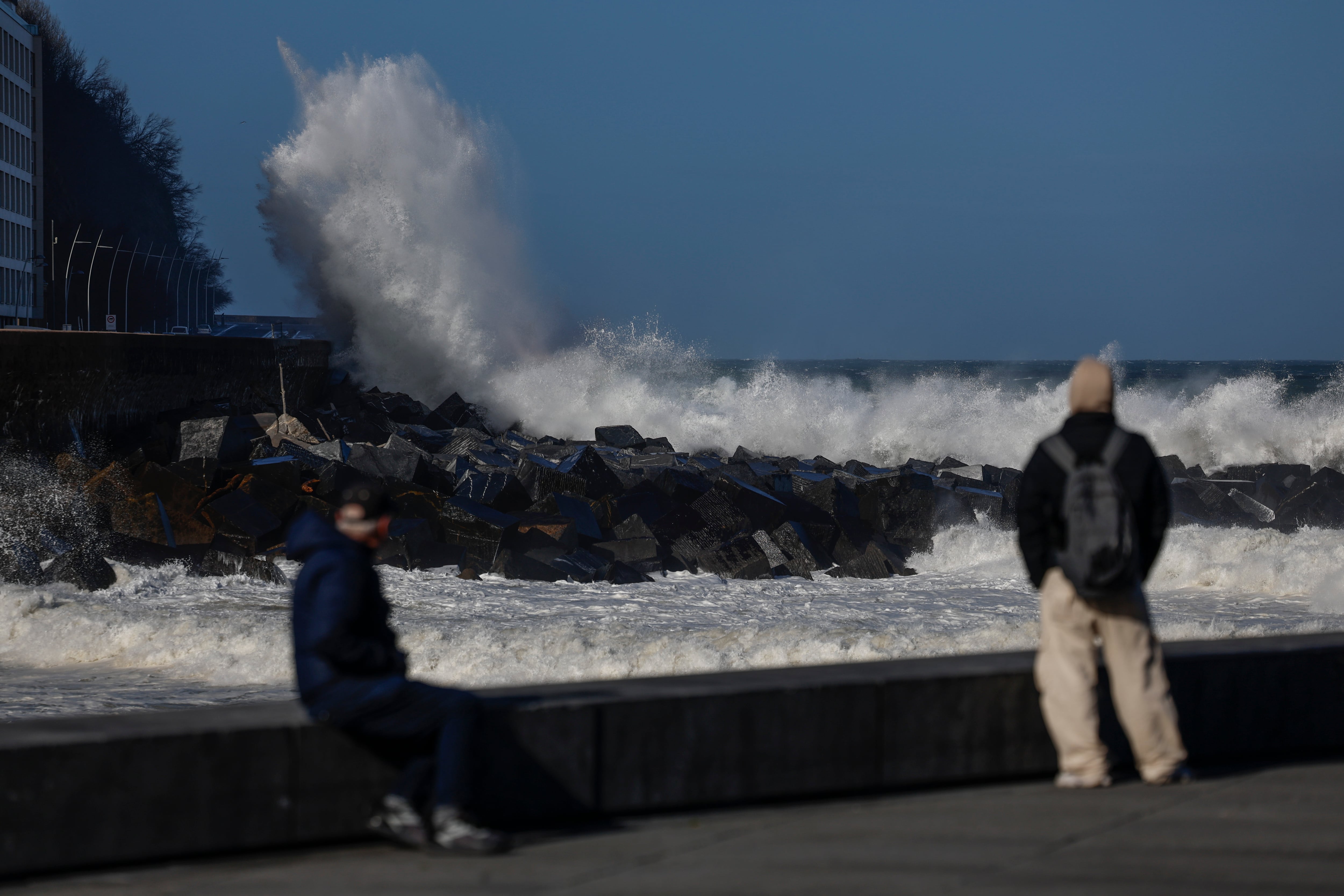GRAFCAV9783. SAN SEBASTIÁN, 12/02/2026.- Donostiarras y visitantes observan el oleaje este jueves en el Paseo Nuevo de San Sebastián. El viento ha soplado con intensidad esta madrugada en Euskadi y superado los 100 kilómetros por hora en varios puntos de la costa y de la montaña con la racha máxima, de 149,6 km/h, localizada en Matxitxako (Bizkaia). EFE/Juan Herrero.
