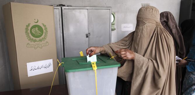 Una mujer con kurca deposita su voto en un colegio electoral en Islamabad este domingo