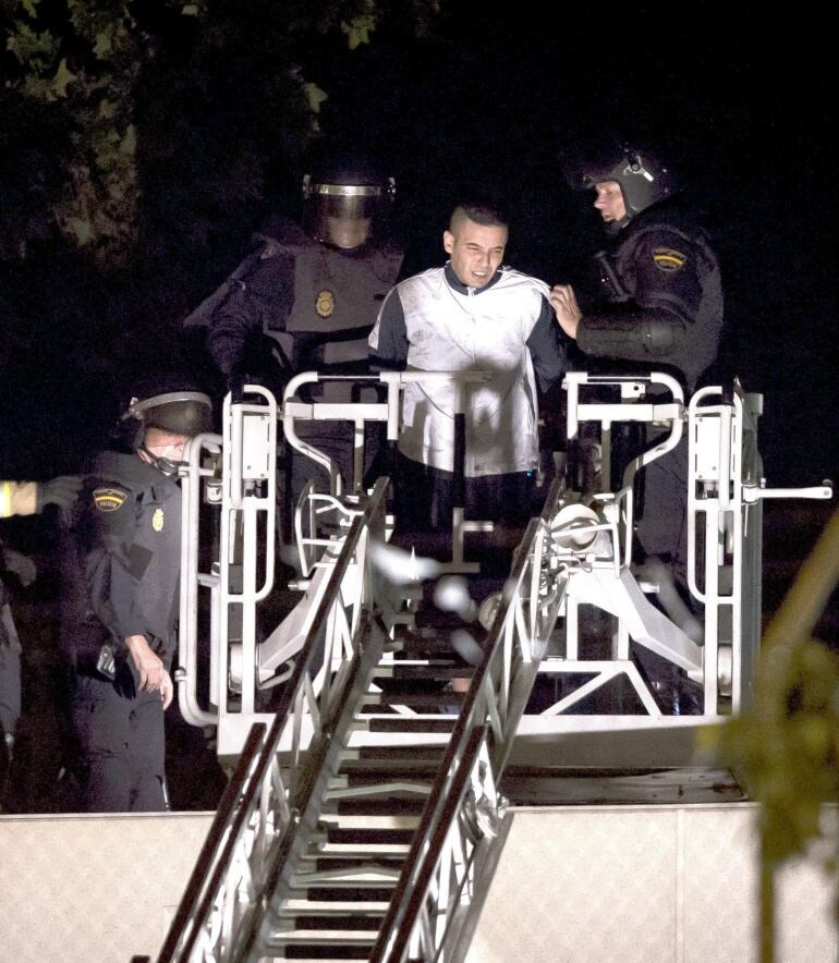 GRA035 VALENCIA (COMUNIDAD VALENCIANA),7/9/2015.- Agentes del Cuerpo Nacional de Policía han abortado esta medianoche con material intimidatorio un motín protagonizado por 54 internos del Centro de Internamiento de Extranjeros (CIE) de Zapadores, en Valencia, seis de los cuales se llegaron a encaramar a uno de sus tejados.en el suceso han resultado lesionados dos agentes, sin que por el momento se conozca si alguno de los amotinados ha resultado herido.En la foto, efectivos de la policía desalojan a uno de los presos amotinados del tejado. EFE/Biel Aliño