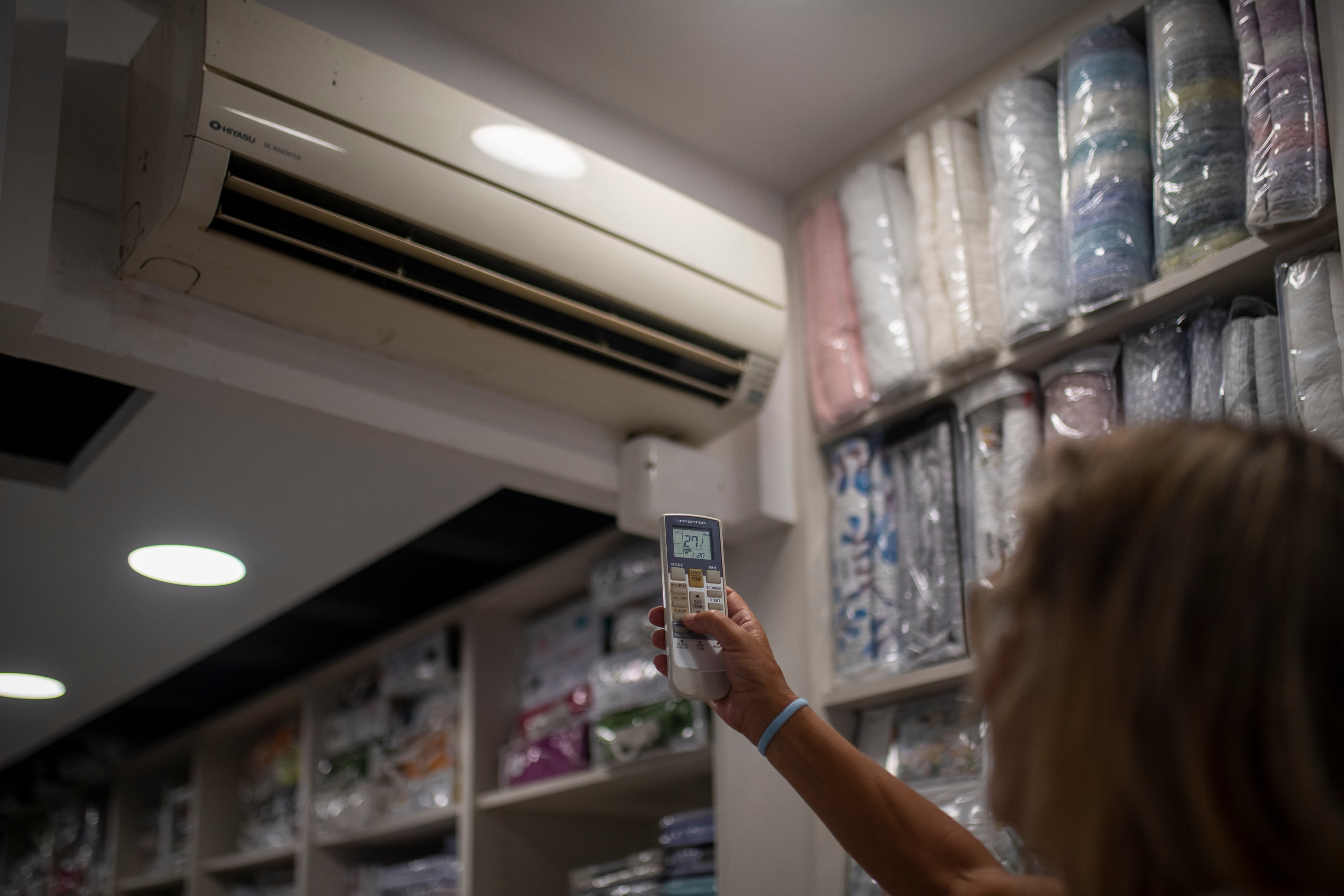 Una trabajadora regula el aire acondicionado en un comercio, en Barcelona.