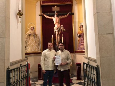 Pedro Sánchez Alvarez, Hermano Mayor de la Expiración, a la derecha, y Jesús Mª Martínez Risquez, Presidente de la Banda Santa Cecilia, muestran el contrato ante el Cristo de la Expiración.