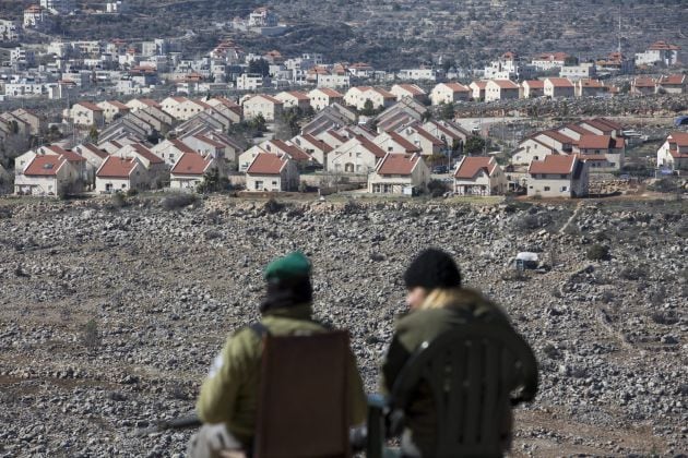 Policías fronterizos israelíes conversan mientras vigilan, con el asentamiento israelí de Ofra al fondo, durante la demolición del asentamiento ilegal judío de Amoná, en Cisjordania