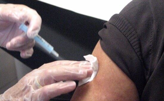 Un professional administra una vacuna contra la grip