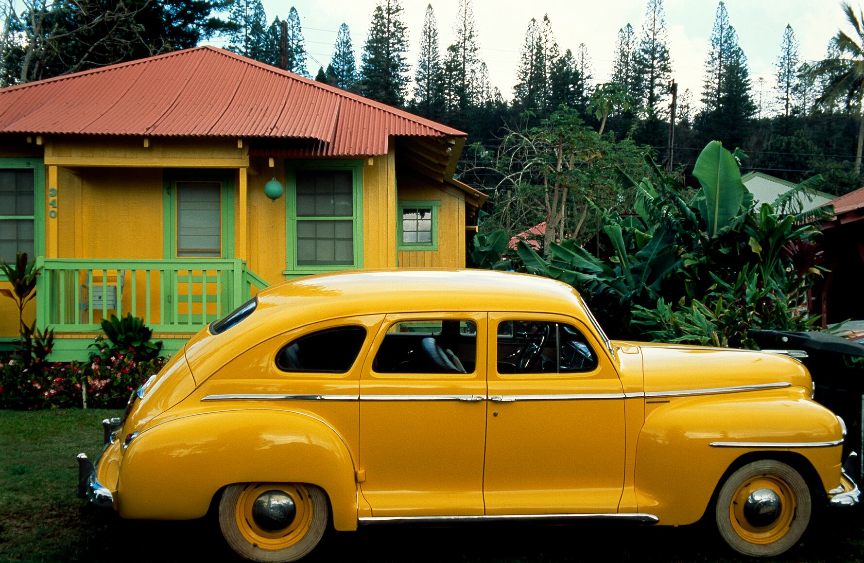 Un Plymouth de color amarillo vivo está aparcado delante de una casita del mismo color en Lana’i City. La mayoría de los 2.800 residentes de Lana’i City siguen viviendo en las mismas casitas pintadas de colores pastel y con tejados metálicos donde vivían los habitantes del lugar cuando trabajaban en las plantaciones de piñas de la isla. Isla de Lanai, Hawái, Estados Unidos