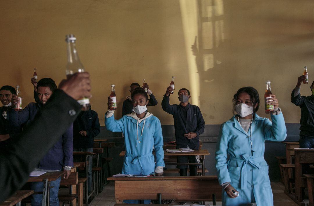 Estudiantes sostienen una botella de Covid Organics, un té de hierbas, promocionado por el presidente de Madagascar, Andry Rajoelina, como un poderoso remedio contra el coronavirus.