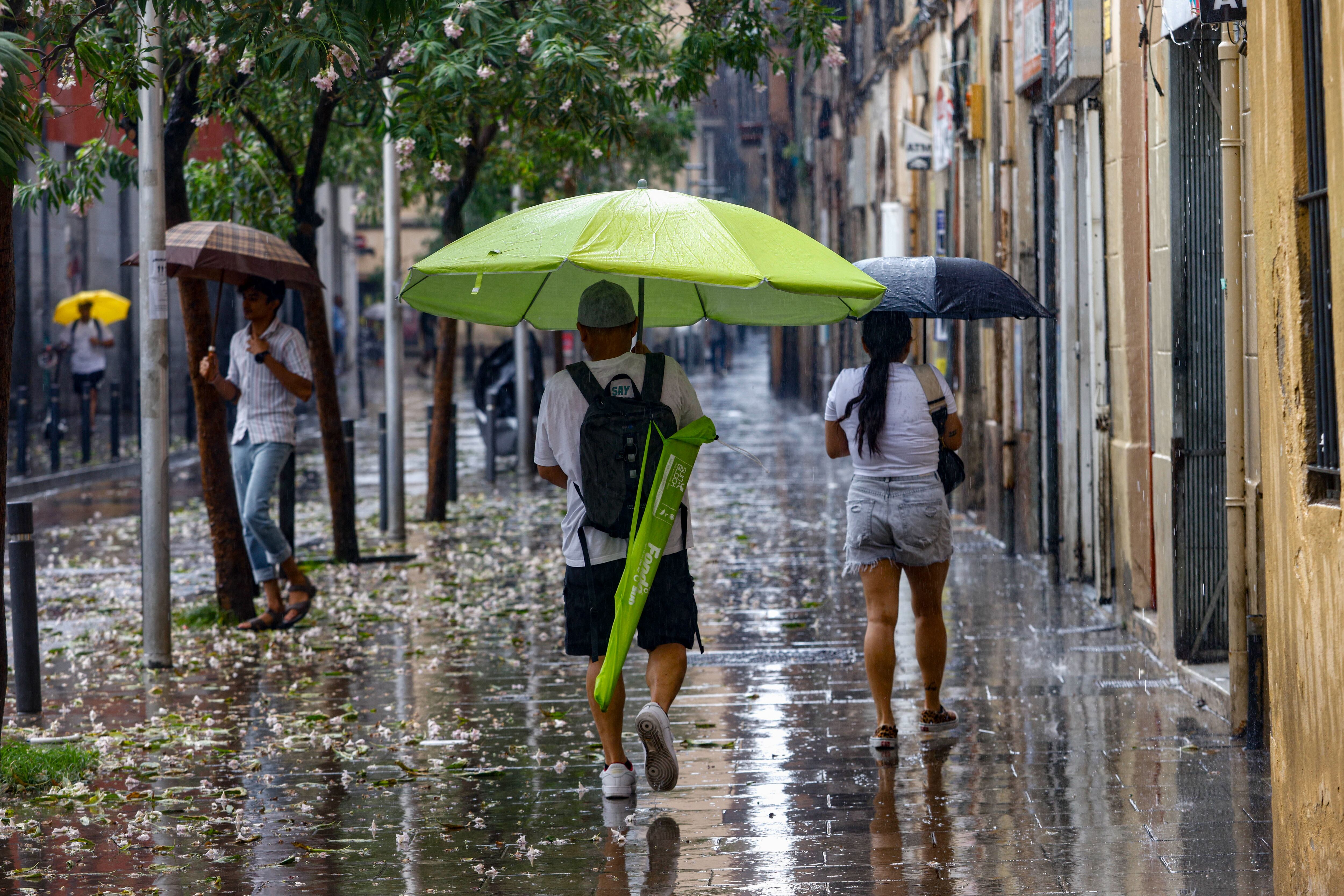 Una persona se protege con una sombrilla de playa en Barcelona.