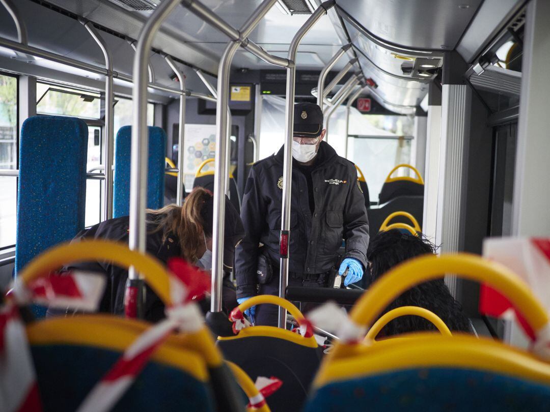 Dos agentes de la Policía Nacional protegidos con mascarillas identifican a viajeros de un autobús urbano en un control en la Avenida del Ejército de Pamplona