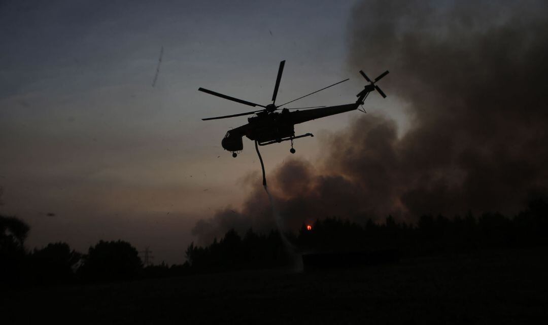 Un helicóptero combate las llamas en los incendios en Kyrone, Grecia