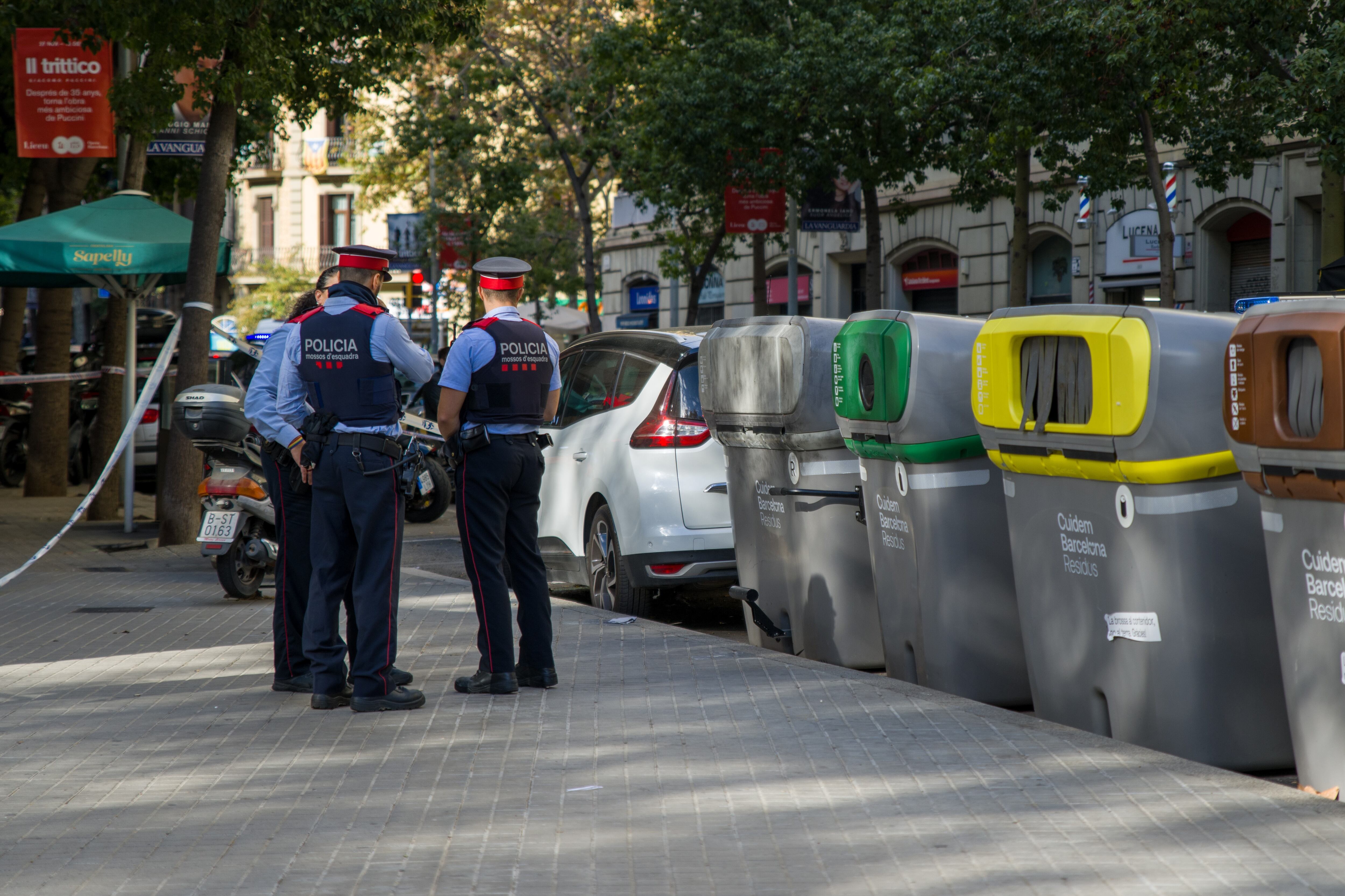 Agents dels Mossos de Esquadra parlen al costat del contenidor en el qual ha aparegut un cadàver mutilat dins d'una maleta, aquest dimarts en el centre de Barcelona