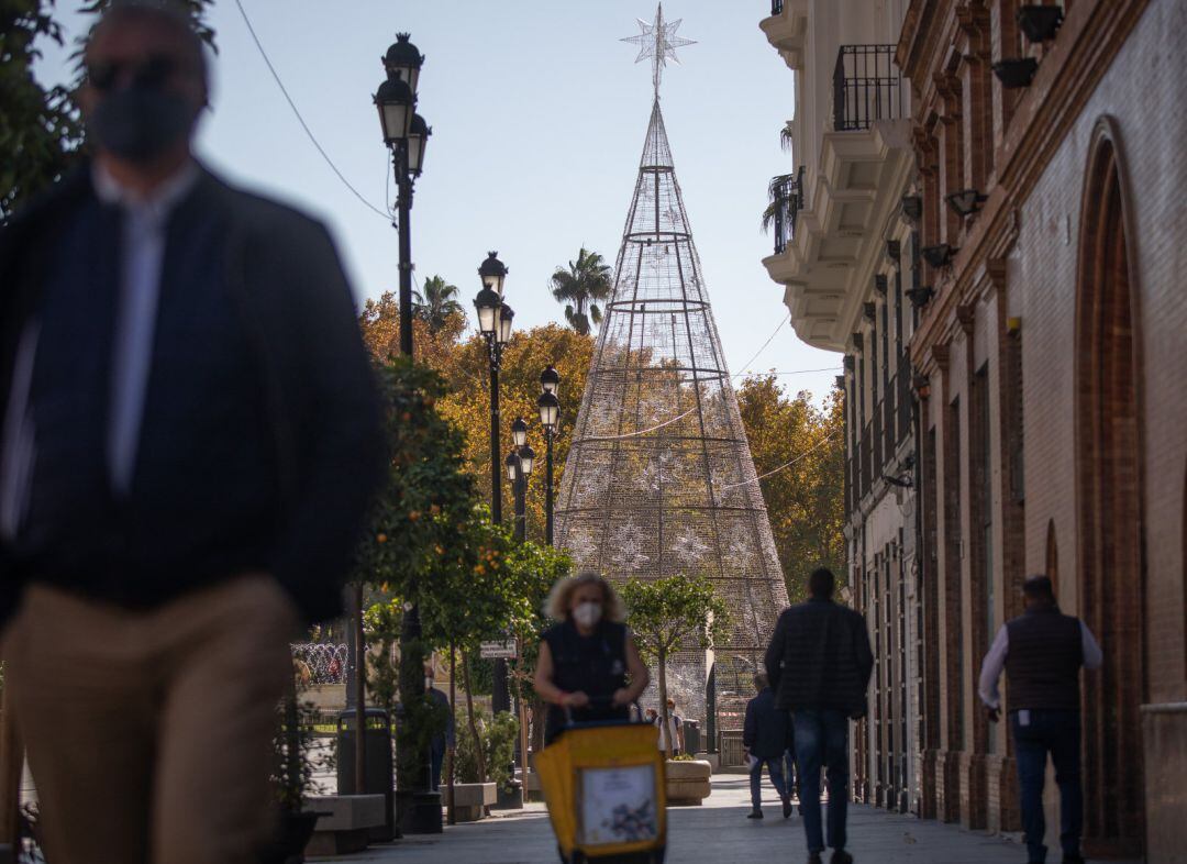 Transeúntes por la Puerta de Jerez en Sevilla, al lado del árbol de Navidad.