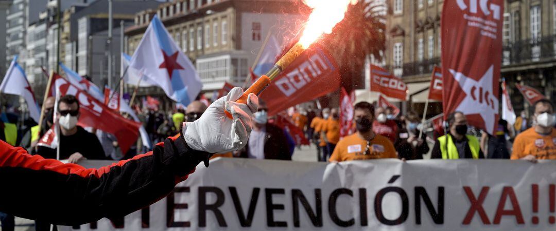 Decenas de personas con banderas de sindicatos y humo durante una manifestación convocada por varios sindicatos&quot;en defensa del empleo, por un futuro industrial, contra la represión sindical en Alu Ibérica&quot;