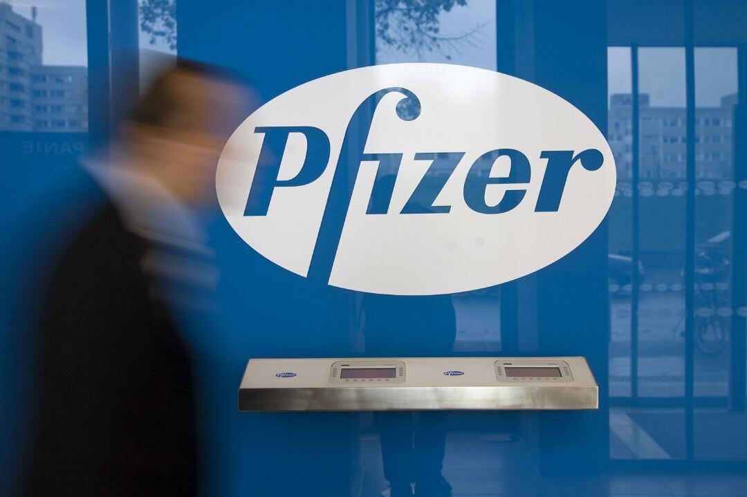 Imagen de archivo de un hombre pasando frente al logo de Pfizer