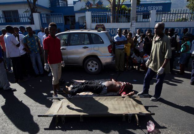 Trabajadores forenses rodean el cuerpo sin vida del policía Simone Jackson este miércoles, en Puerto Príncipe (Haití). El policía y dos conductores de transporte público murieron este miércoles en Martissant, en Puerto Príncipe, cuando miembros de una banda armada dispararon en su contra, aumentado la tensión que se vive en la nación tras las protestas de estos días que han dejado al menos nueve muertos