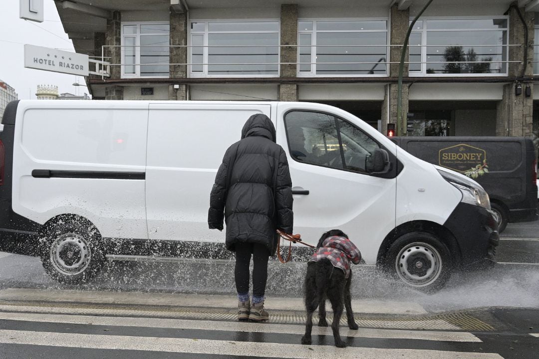 Una mujer espera con su perro antes de cruzar por un paso de cebra 