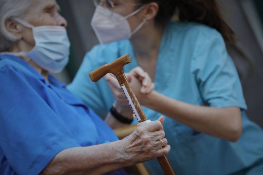 Una anciana siendo ayudada por una trabajadora en una residencia