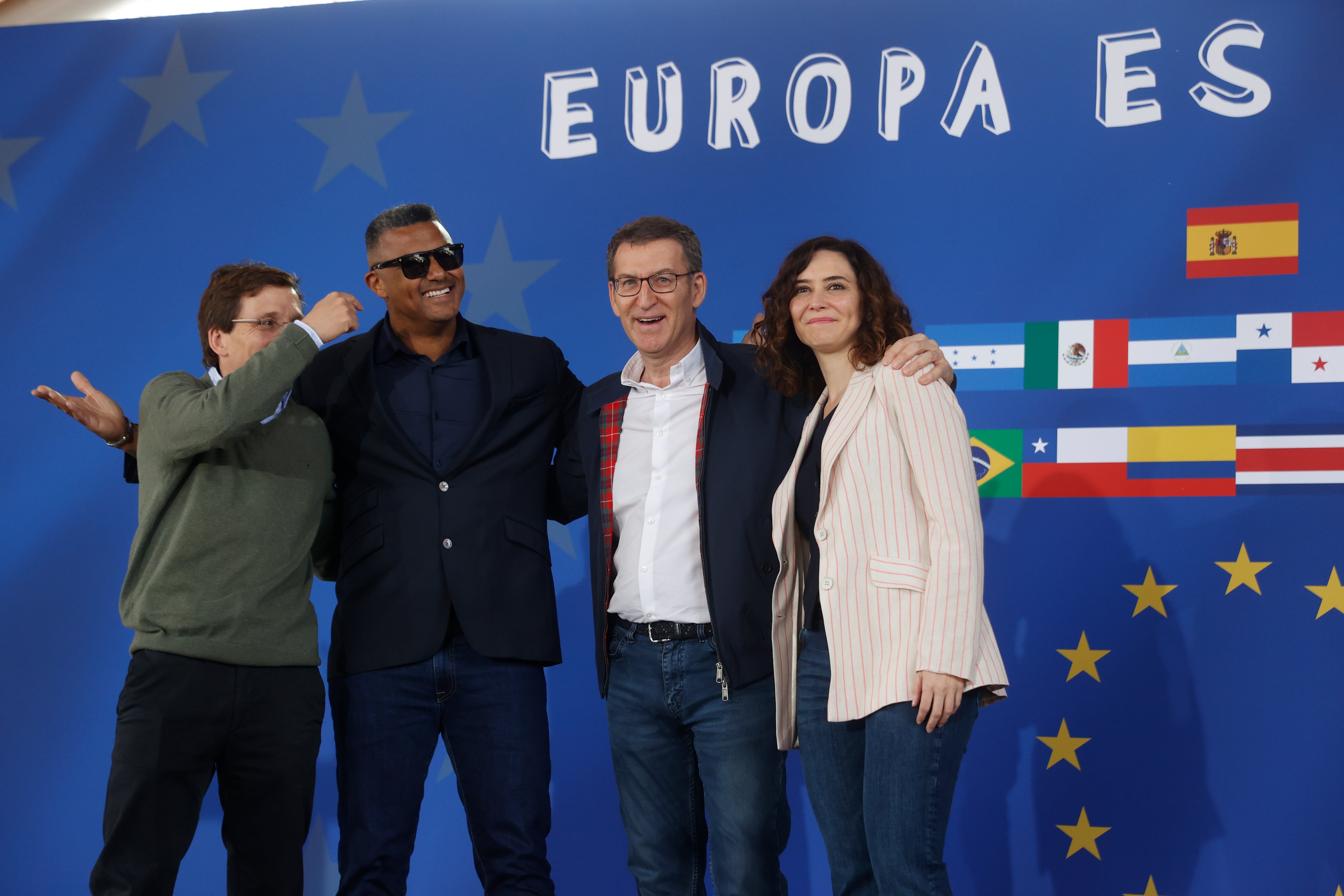 El presidente del PP, Alberto Núñez Feijóo (2d), la presidenta madrileña, Isabel Díaz Ayuso, y el alcalde de Madrid, José Luis Martínez-Almeida (i), junto al cantante dominicano Henry Méndez (2i), este sábado durante el acto del PP en Madrid con hispanos residentes en España, bajo el lema Europa es Hispana || EFE/Juan Carlos Hidalgo